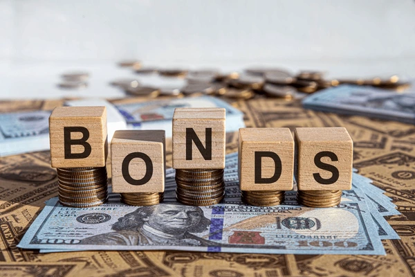 บล็อคไม้ต่อกันเป็นคำว่า BONDS โดยวางไว้บนเหรียญและธนบัตรดอลล่าสหรัฐฯ จำนวนมาก เพื่อสื่อถึงการลงทุนใน Bond CFD 