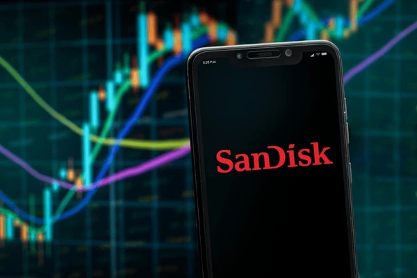หน้าจอโทรศัพท์กำลังแสดงโลโก้ SanDisk และด้านหลังเป็นกราฟราคาหุ้น SNDK แสดงแนวโน้มขาขึ้น 
