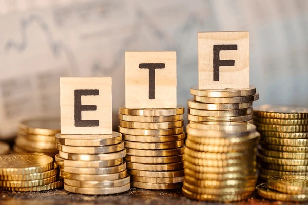 บล็อคไม้ที่เรียงกันเป็นคำว่า ETF ที่วางอยู่บนเหรียญทองคำ สื่อถึงกองทุนทองคำ SPDR Gold Trust (GLD) 